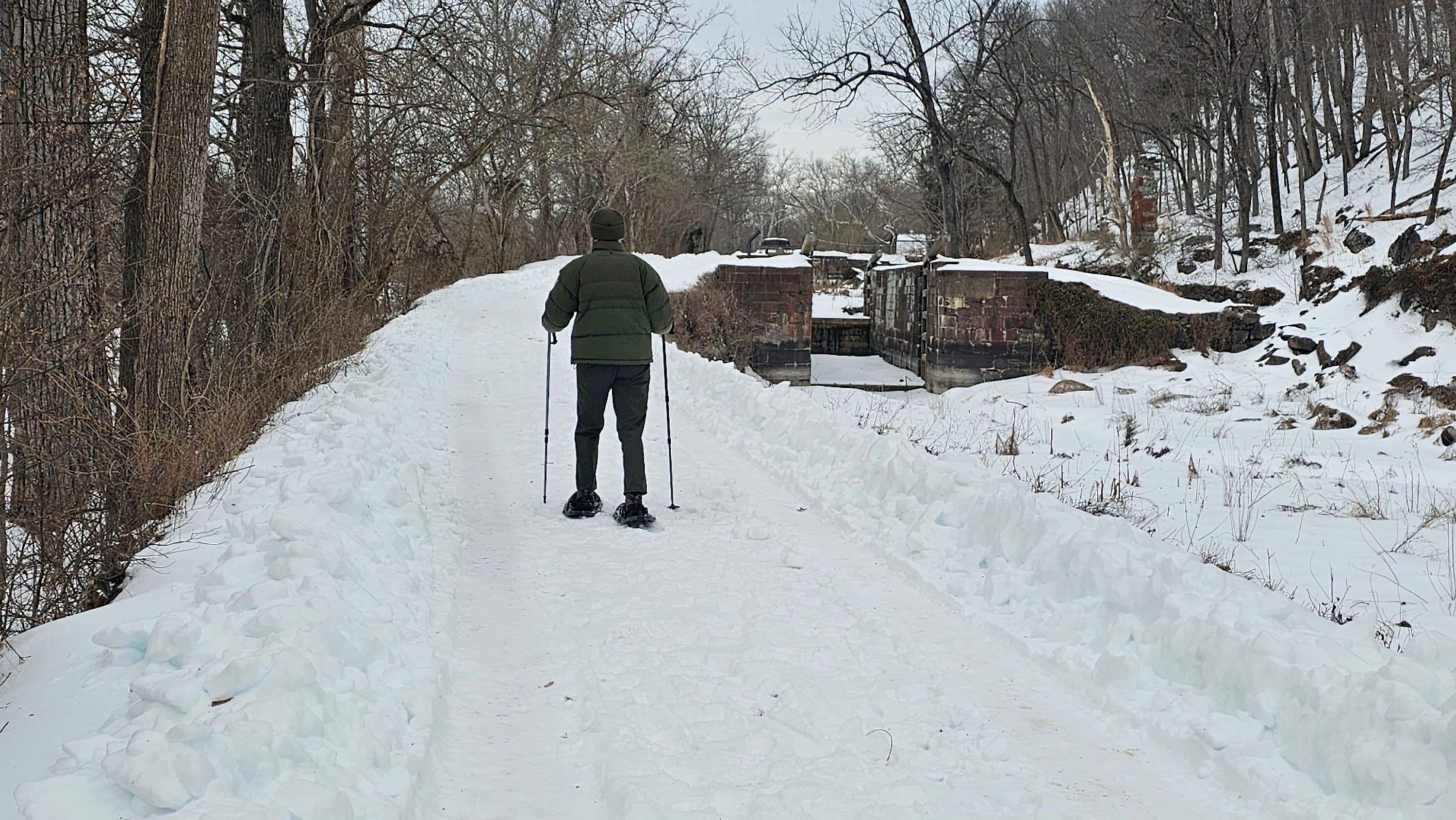 Person dressed in green walking on a snow path