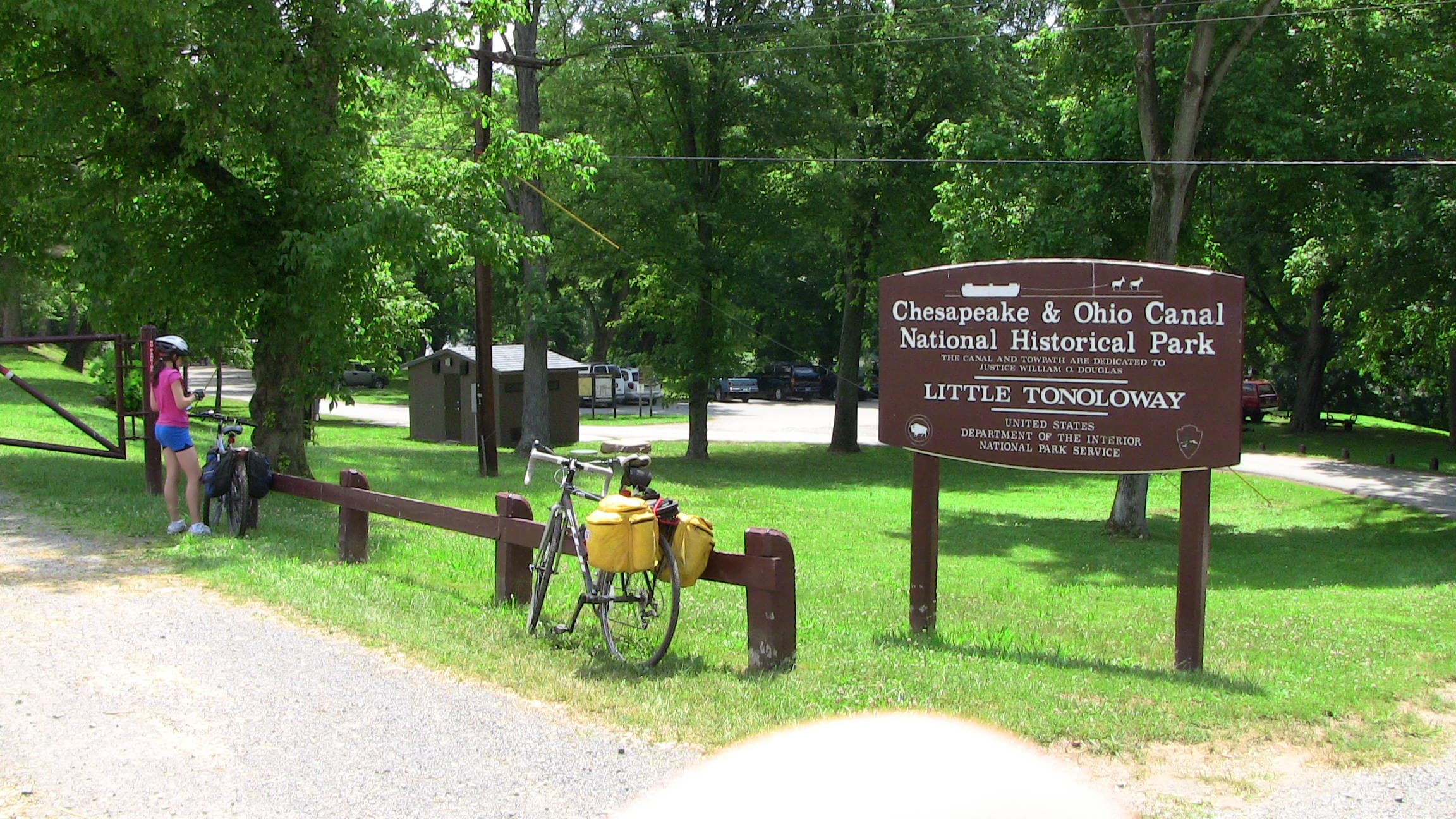 bicyclists stopped along a natural surface path near a modern and an historic historic