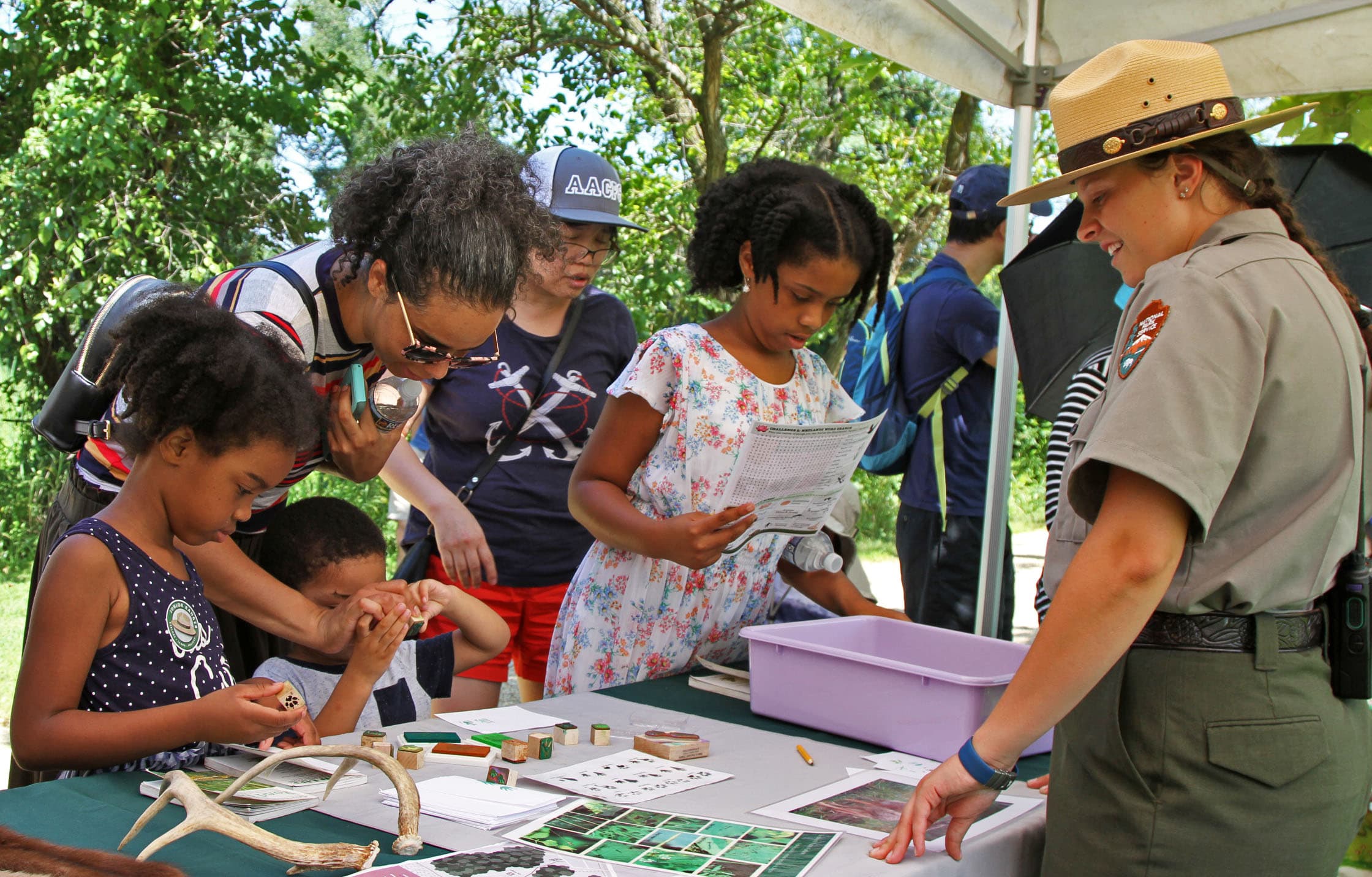 a group of kids with a park ranger looking at antlers on a table.