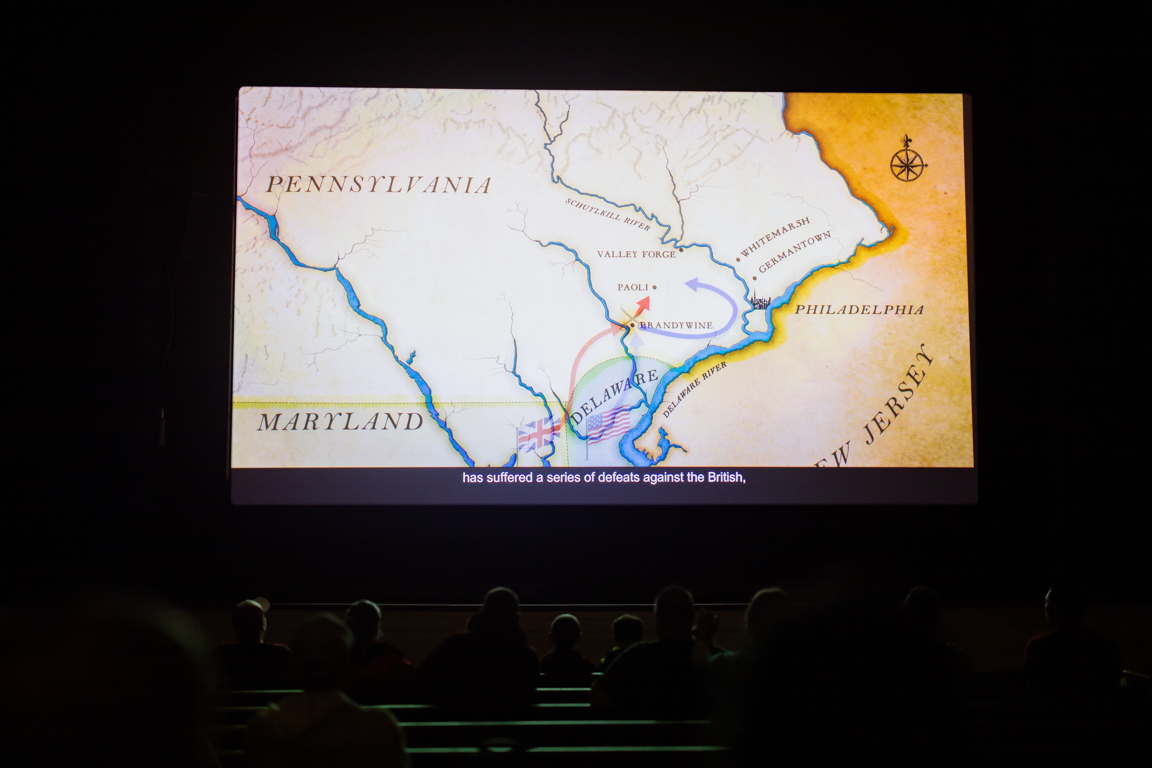Photo of a darkened theater illuminated by a bright screen.