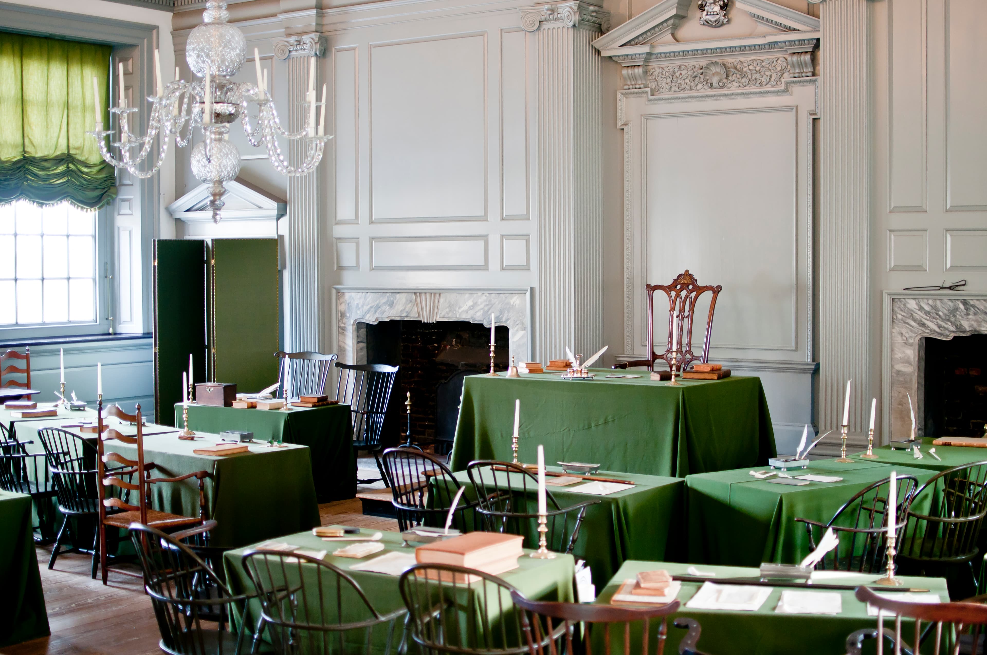 View of room interior showing two rows of tables facing a single chair and table on a dias.