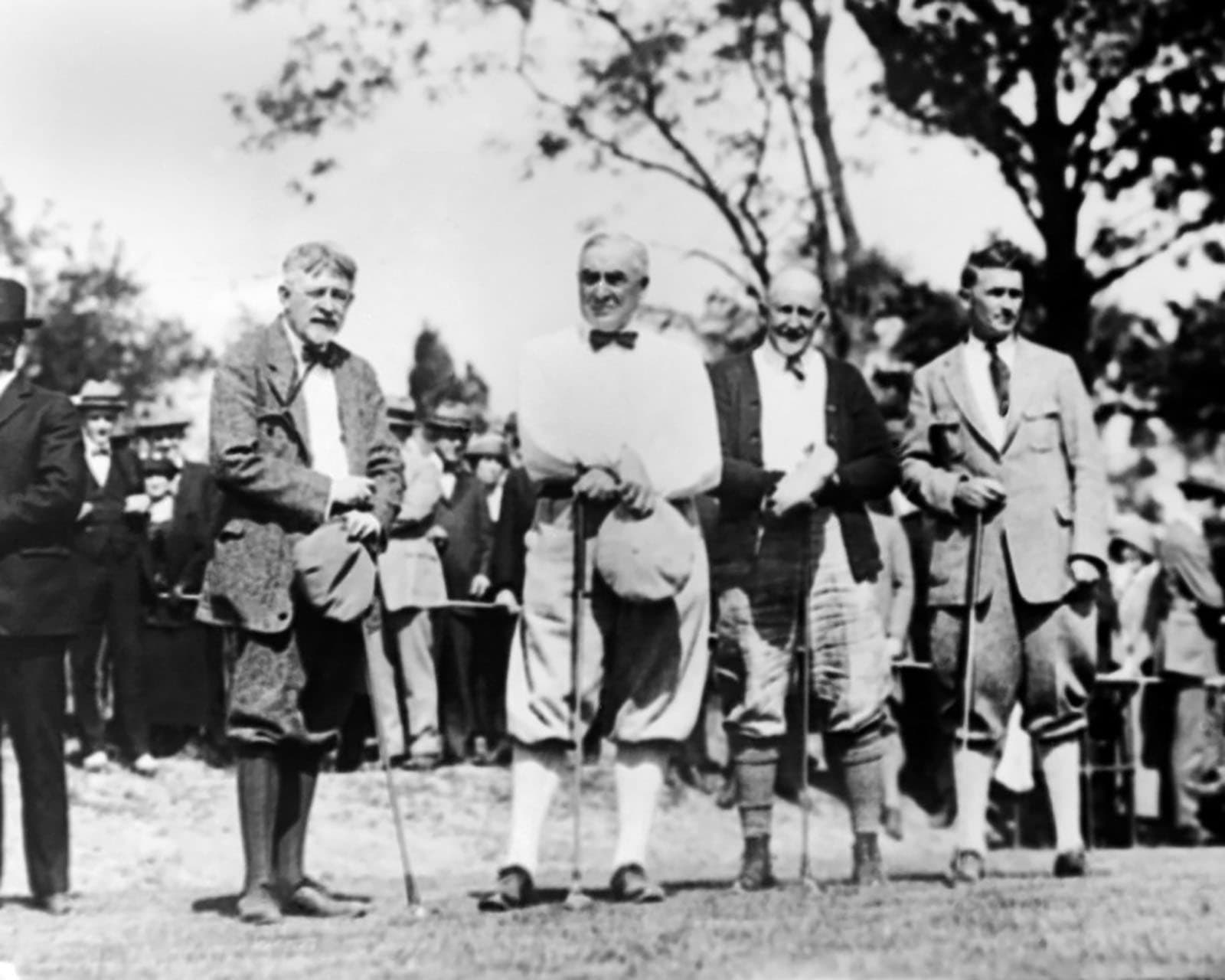 a black and white image of four men wearing dated golfing attire
