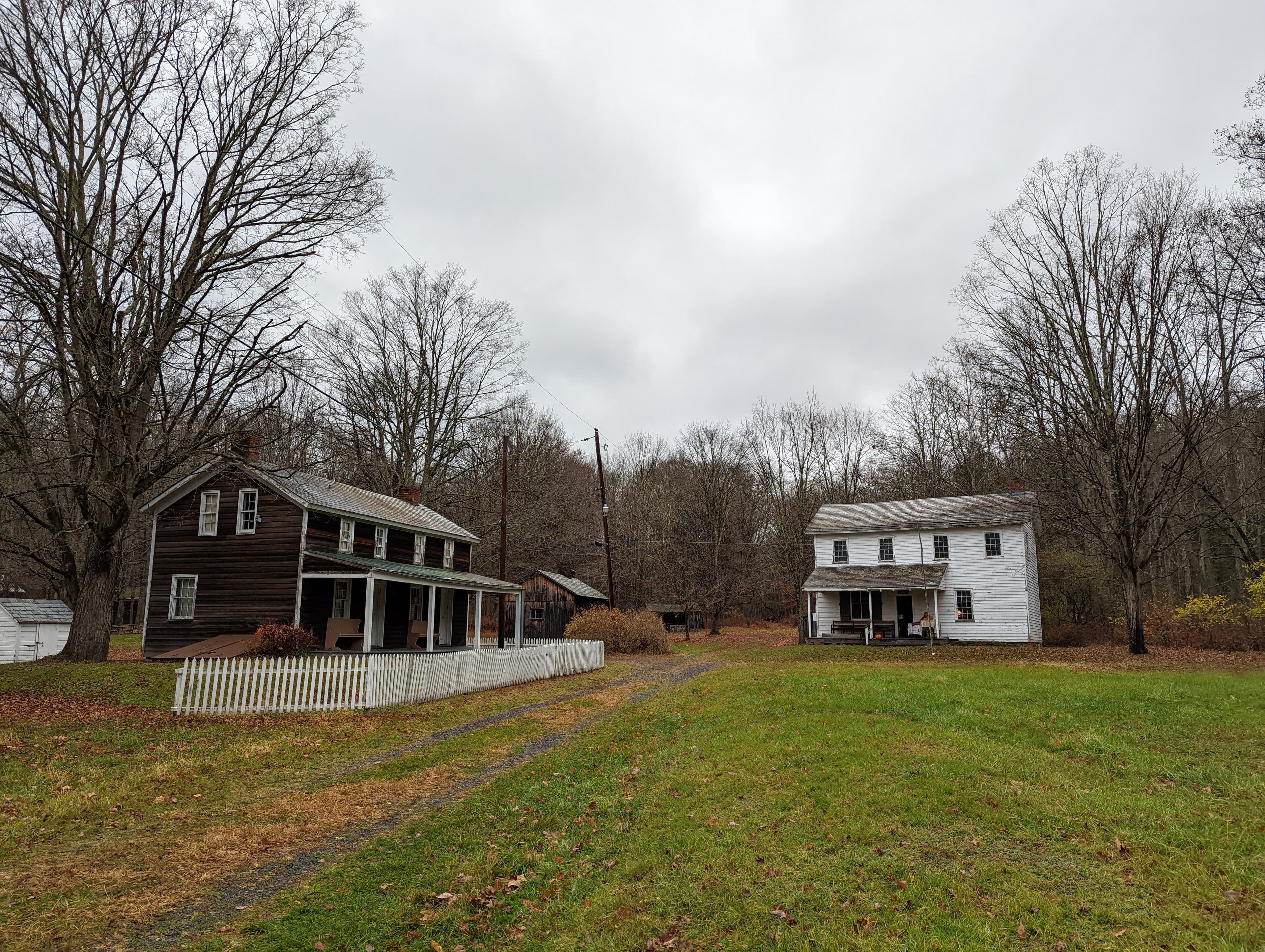 A brown inn with a white fence on the left. A white two-story general store building on the right.