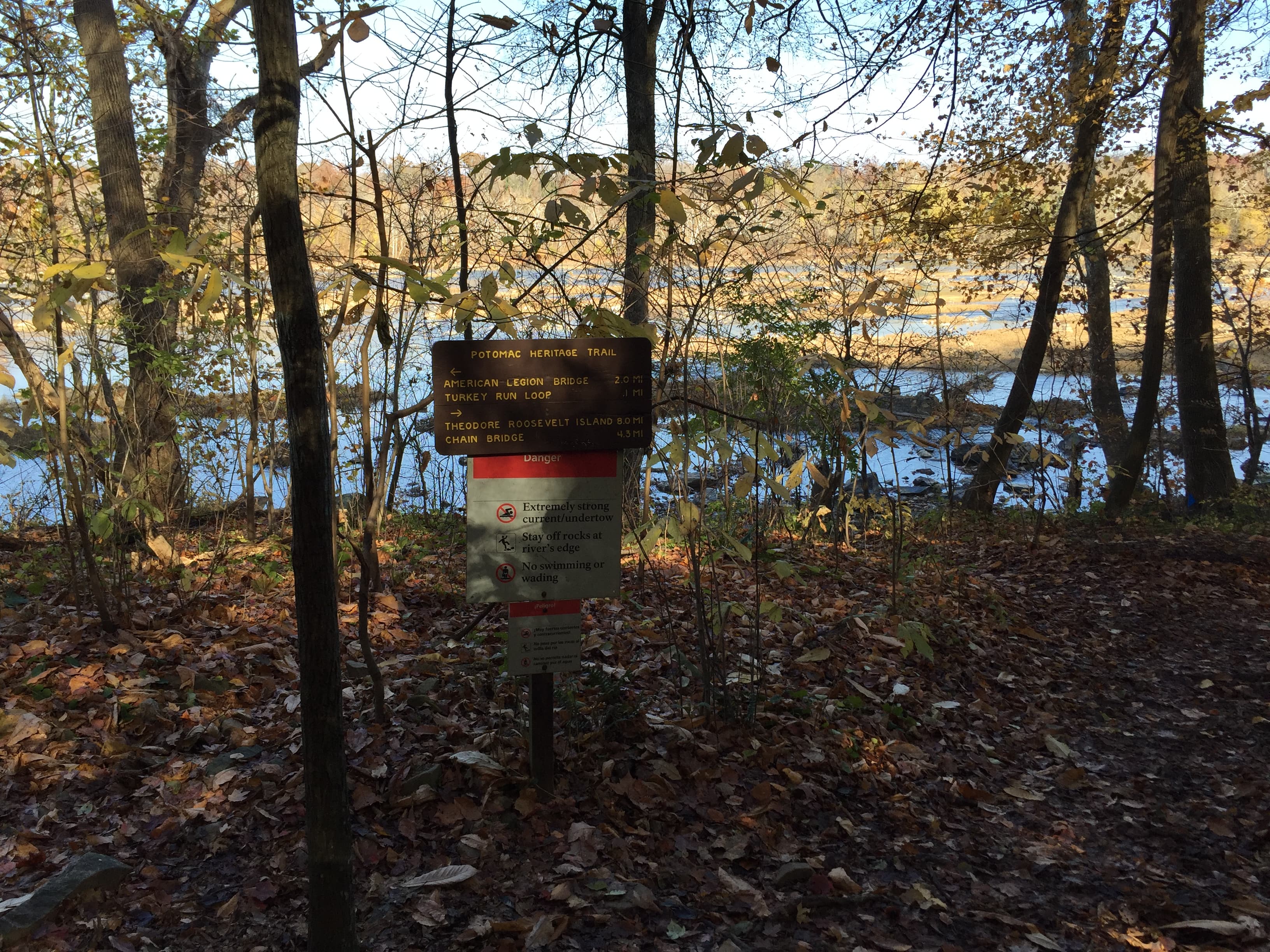 a wooden sign for the Potomac Heritage Trail in a forested riparian area