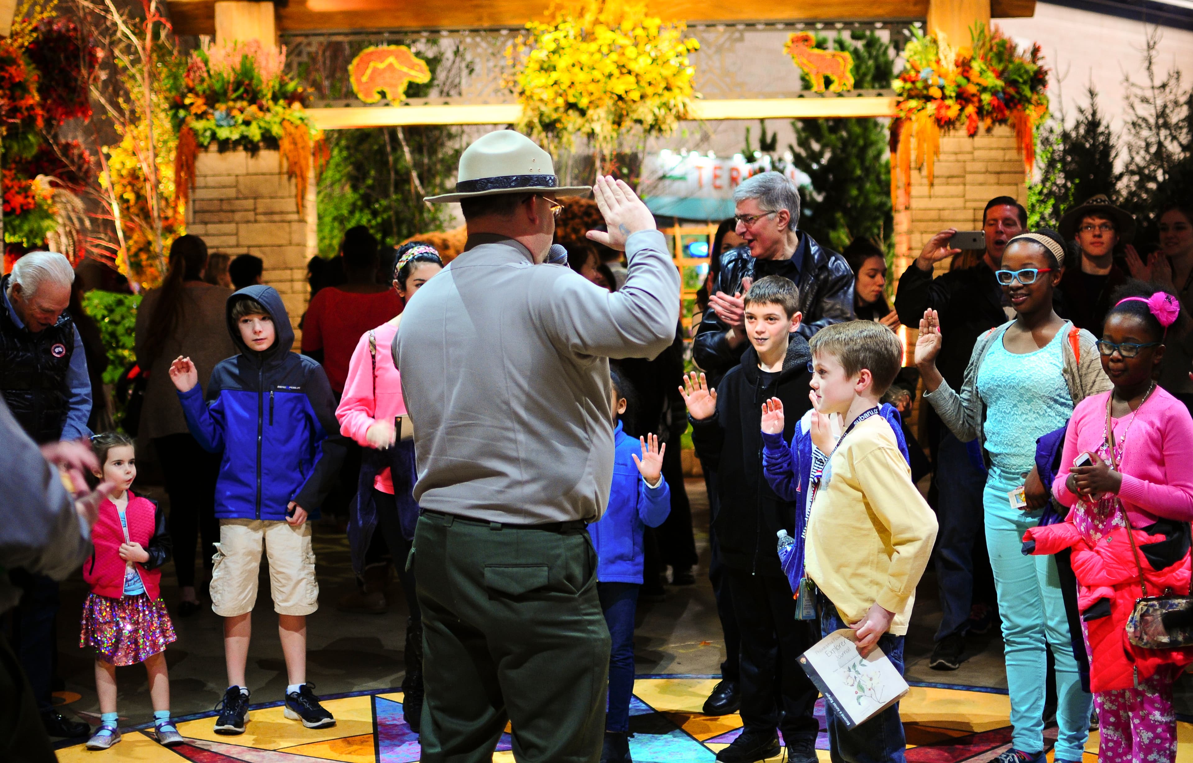 Children facing park ranger raise their right hands to take the oath of Junior Ranger.