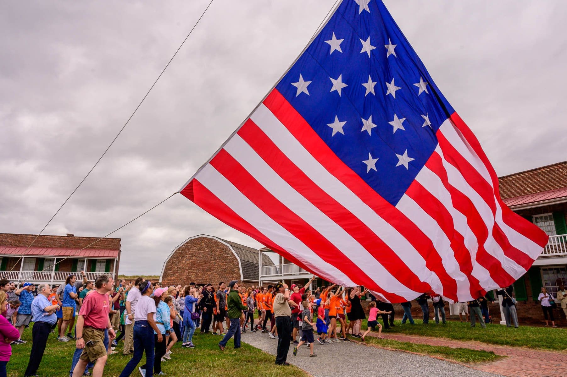 A group of visitors help raise a large garrison flag over Fort McHenry
