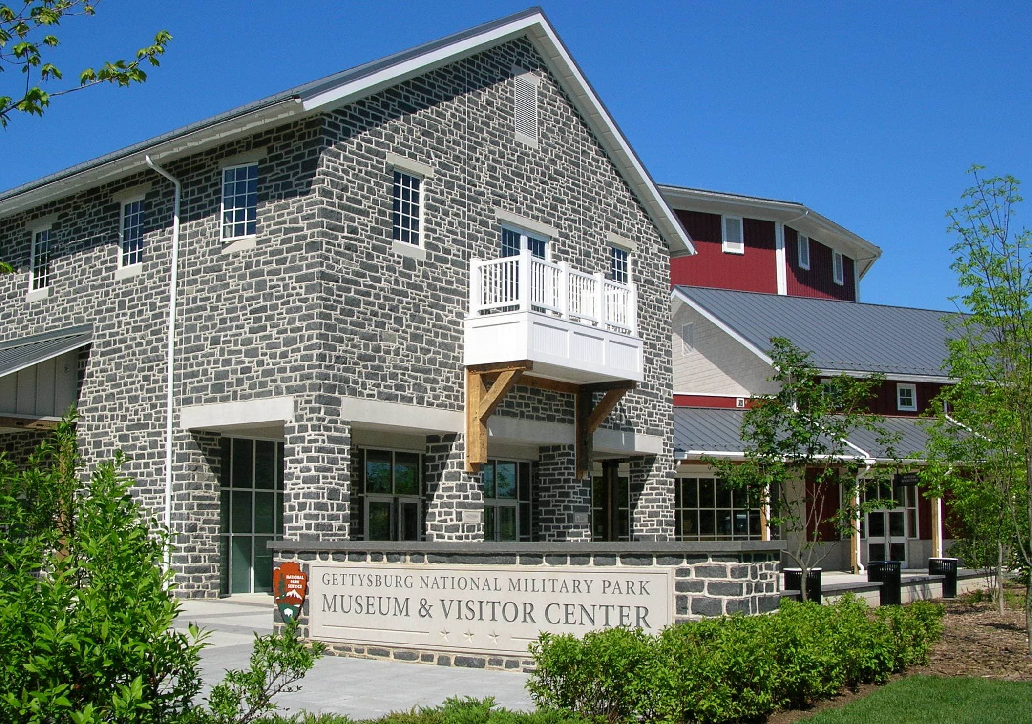 A large stone building with a red barn structure in the background